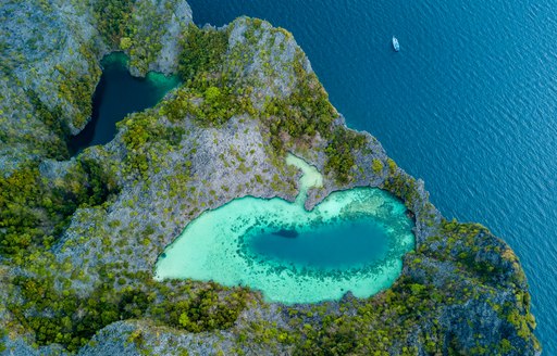 an aerial shot of a bright turquoise lagoon on a rocky island in myanmar