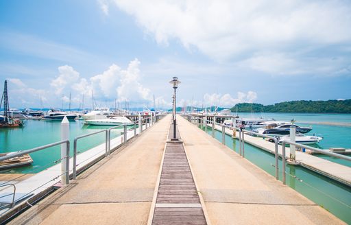 a marina pontoon projects directly out into the sea with yachts