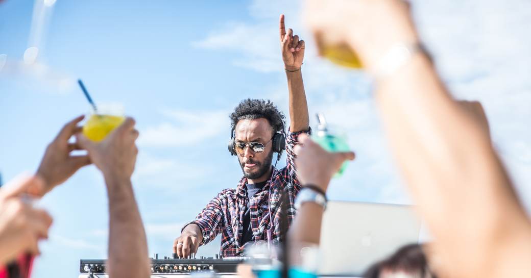 DJ raising his hand, dancing at a beach club in Ibiza 