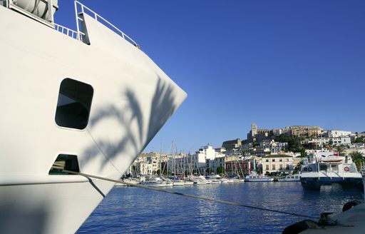 A motor yacht moored in a marina in Ibiza against a bright blue sky