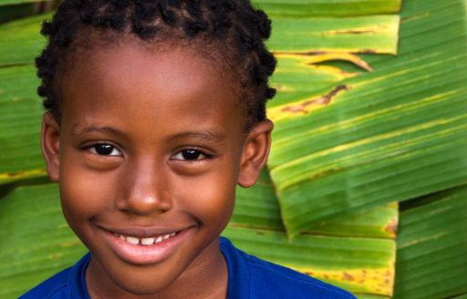 A smiling young boy in front of huge banana leaves