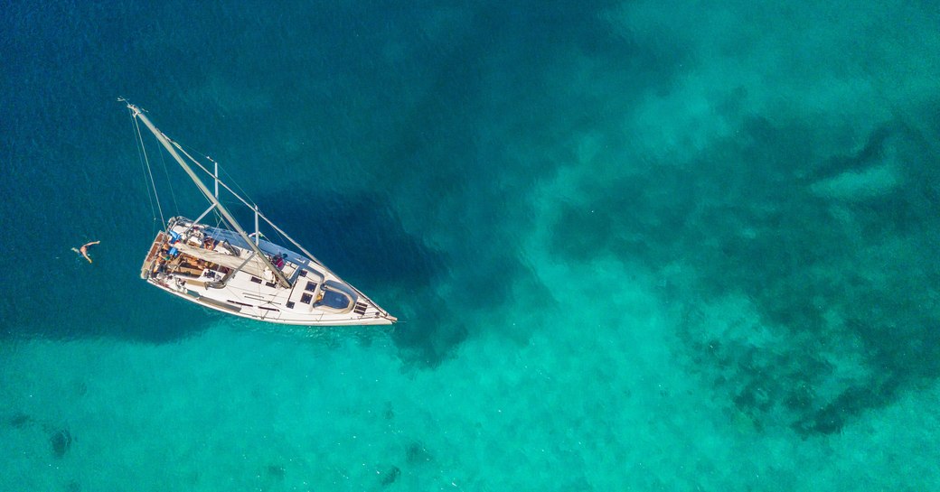 aerial shot of sail yacht anchored in turquoise waters in maldives