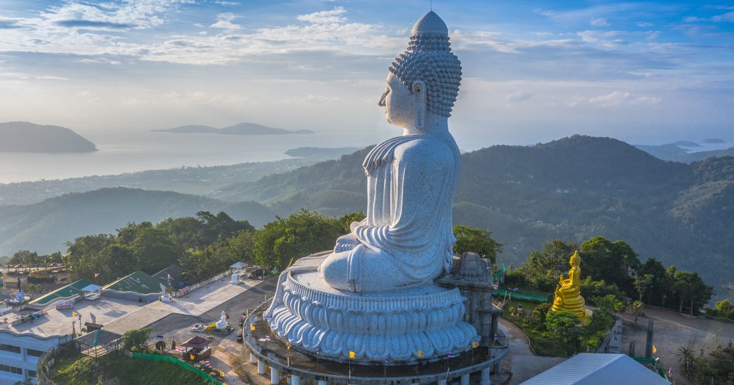 a white marble statue sits atop a mountain in Phuket